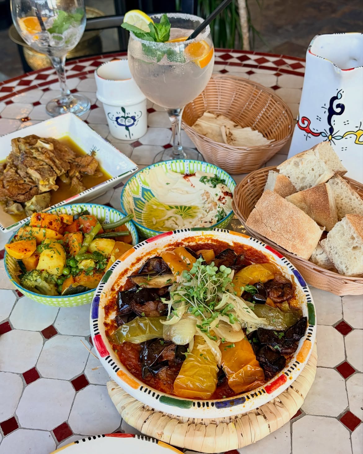 An overhead table of hand-painted Casablanca dishes, bread baskets and mocktails on mosaic tiling